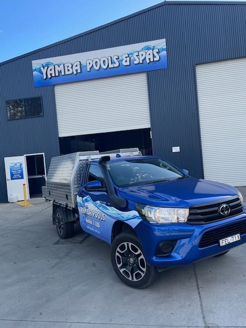 A Blue Truck Is Parked In Front Of A Yamba Pools And Spas Building — Yamba Pools & Spas In Yamba, NSW