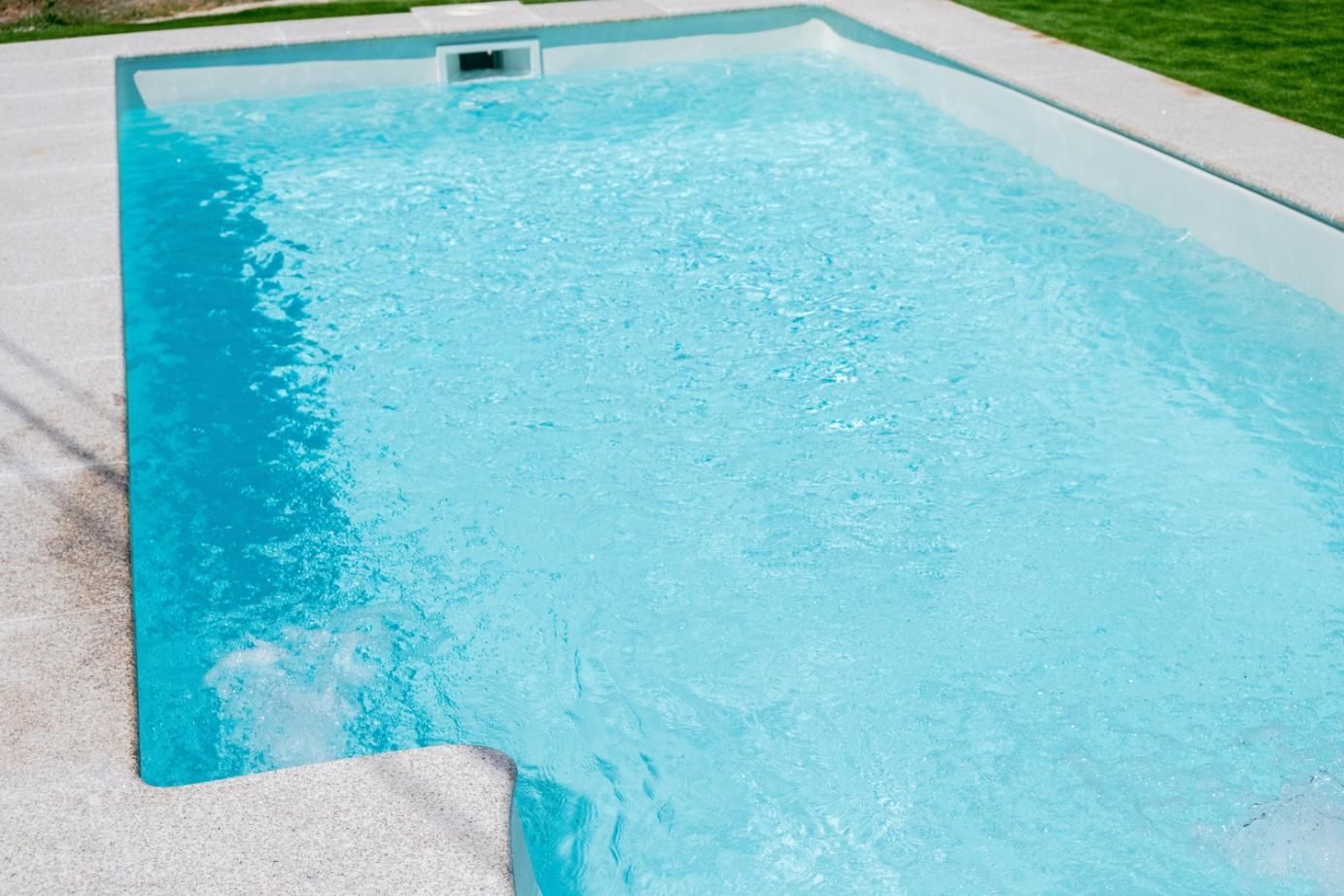 A Large Swimming Pool Filled With Blue Water In A Backyard — Yamba Pools & Spas In Yamba, NSW