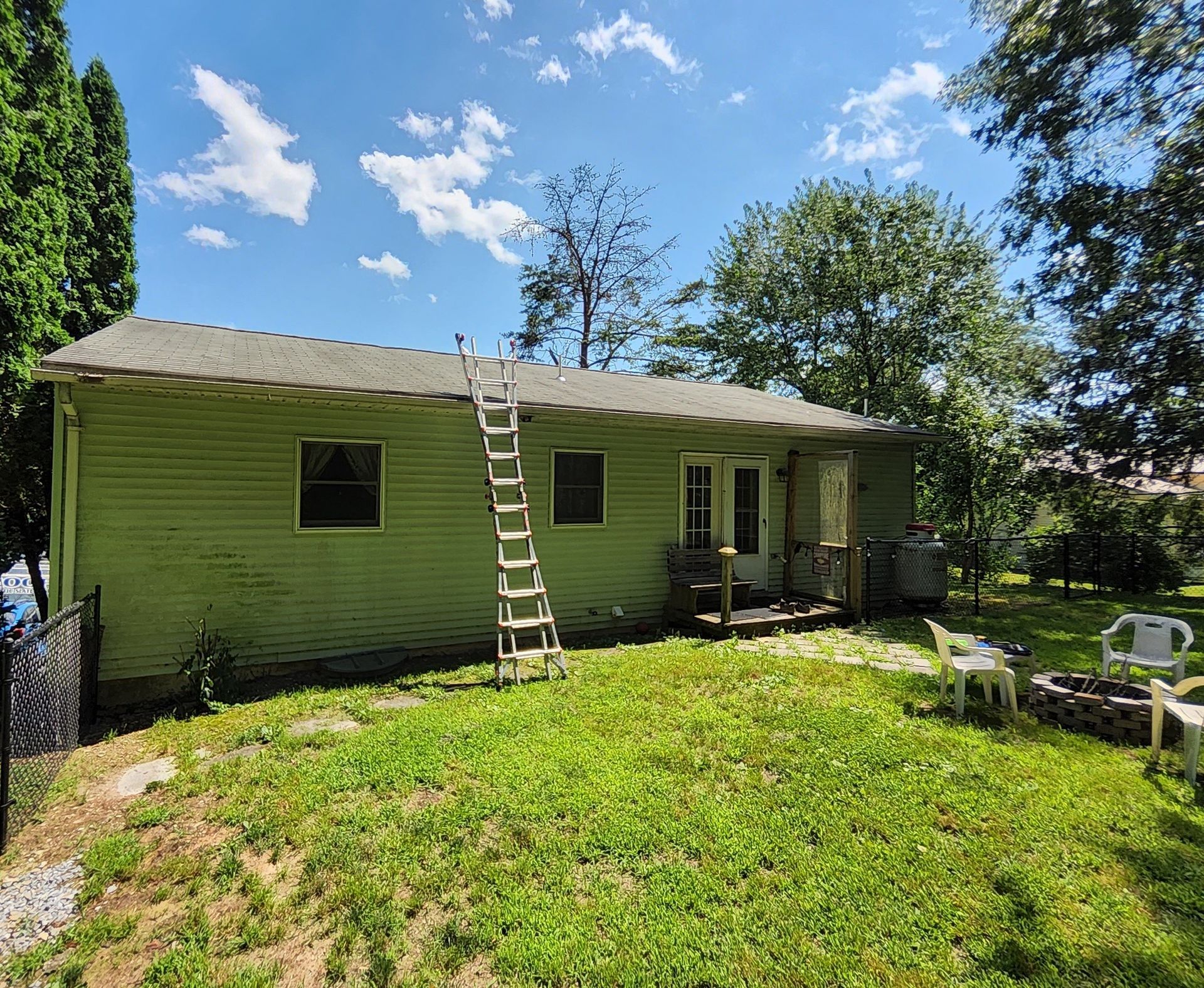 A green house with a ladder on the side of it