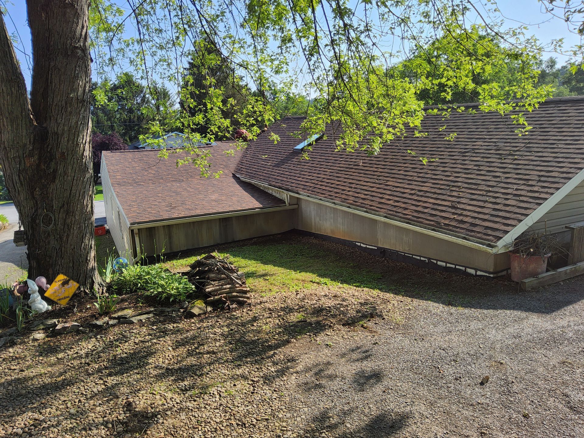 A house with a brown roof and a tree in front of it.