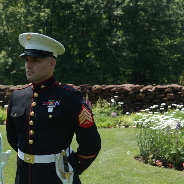 A man in a military uniform is standing in the grass