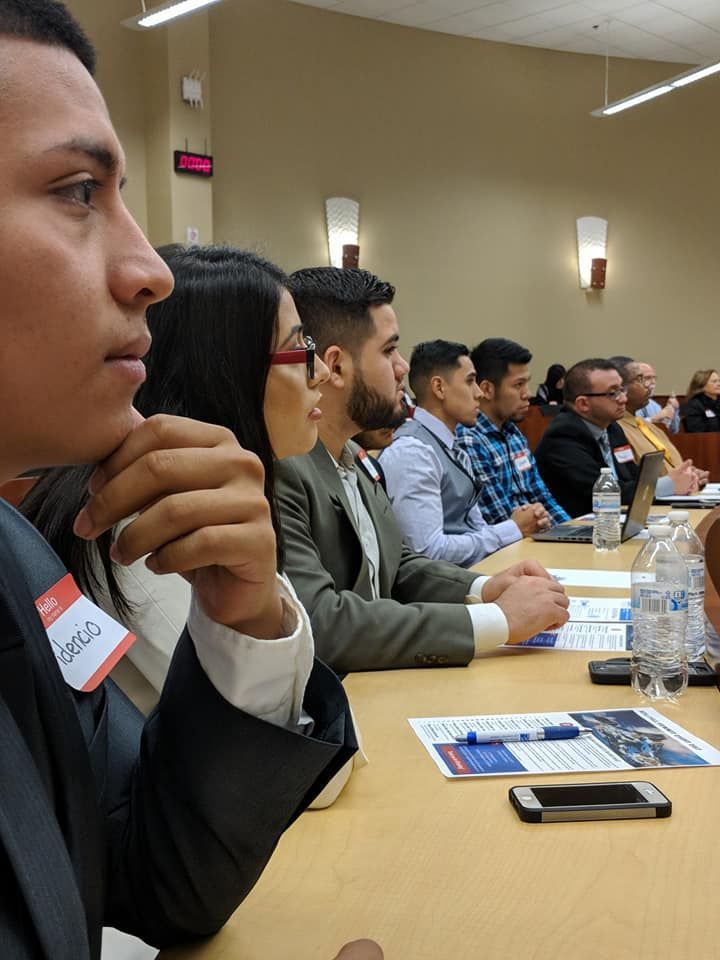 A group of people are sitting at a table with water bottles