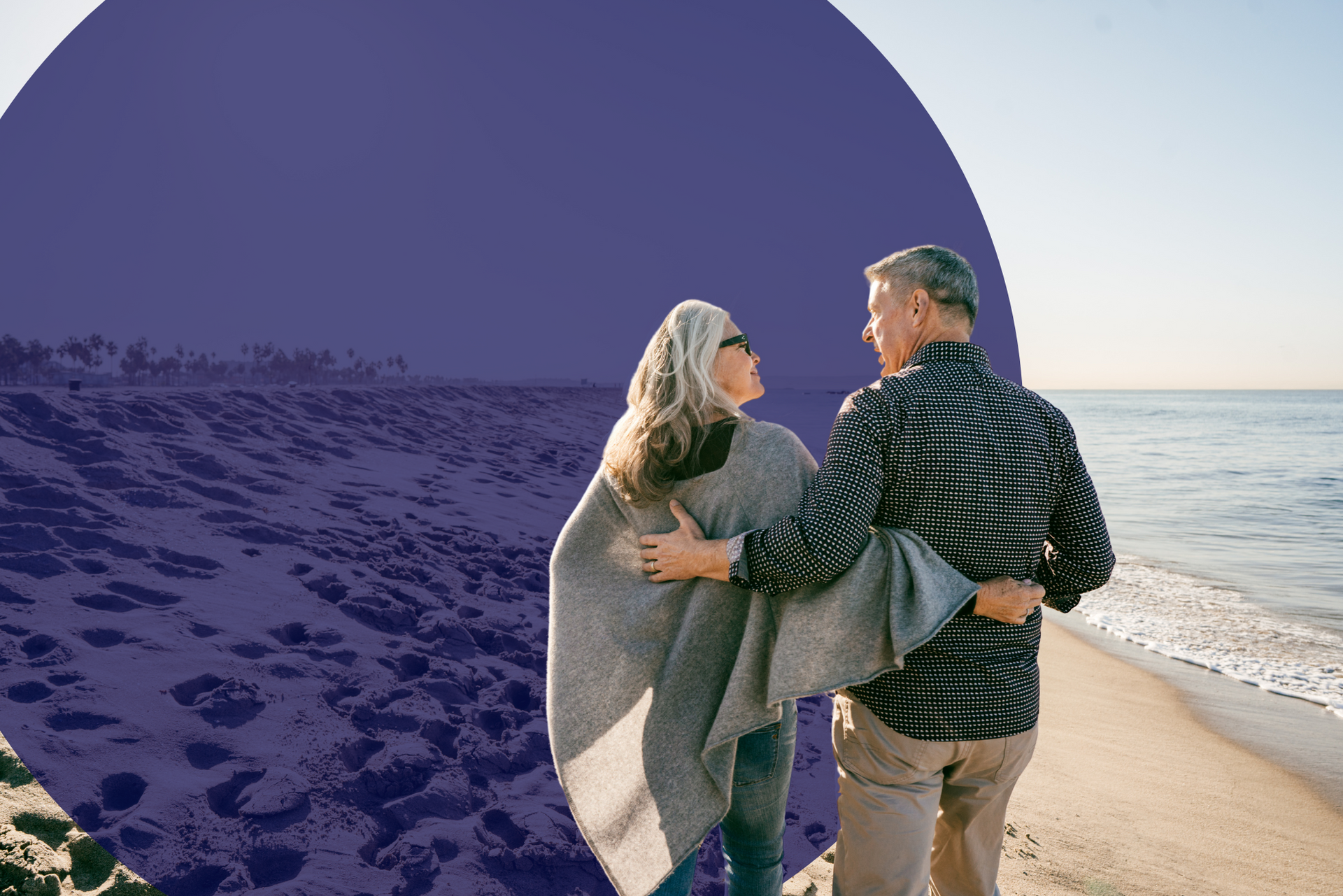 A man and a woman are standing on a beach looking at the ocean.