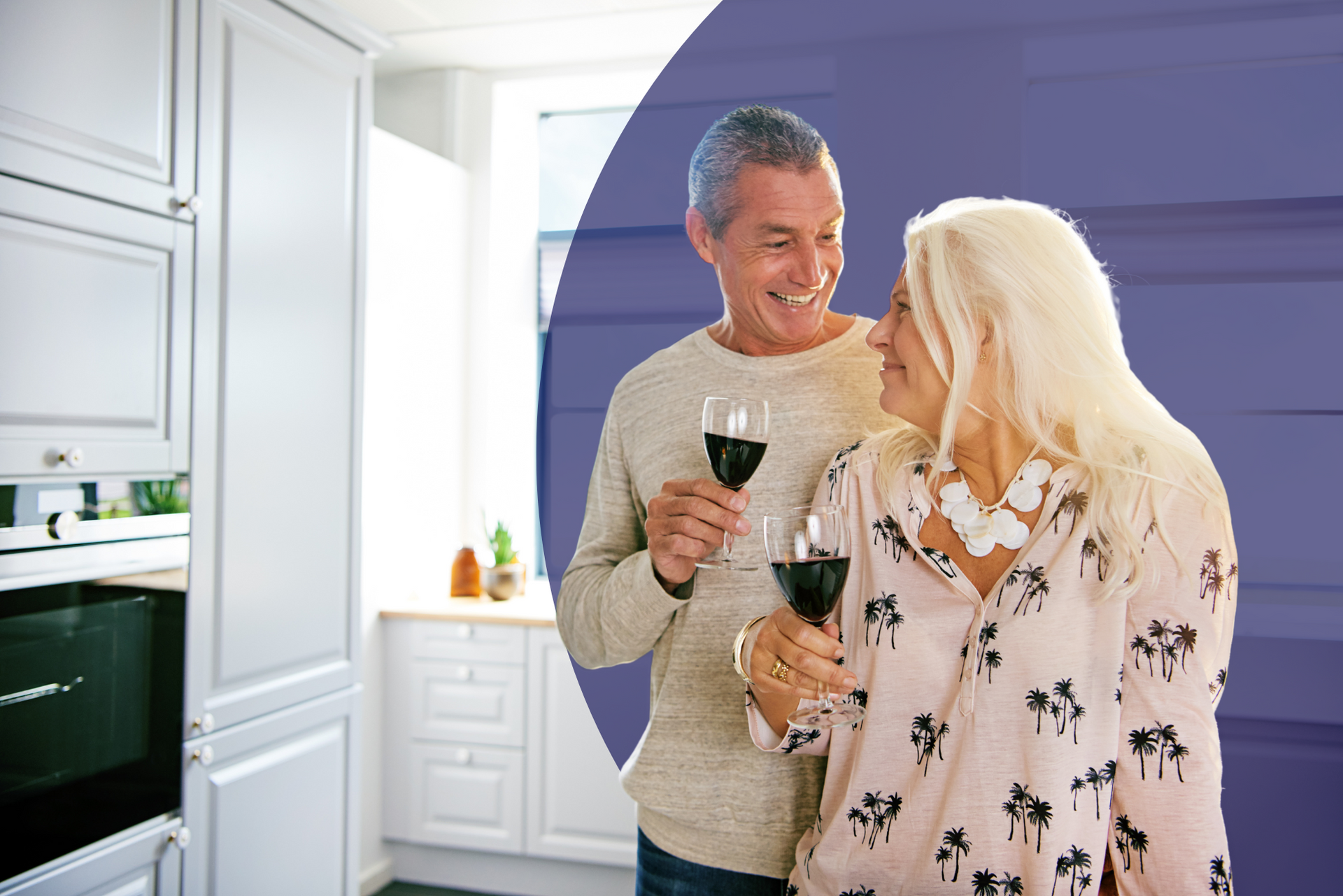A man and a woman are standing in a kitchen holding wine glasses.
