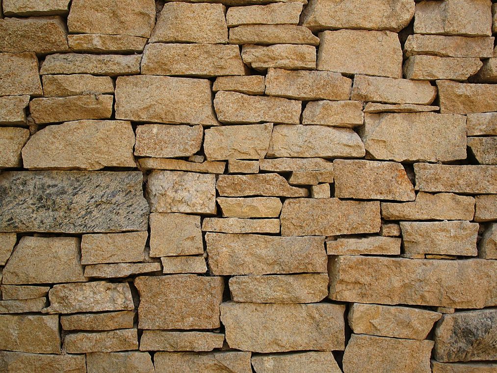 Tan stone wall with varied rectangular shapes.