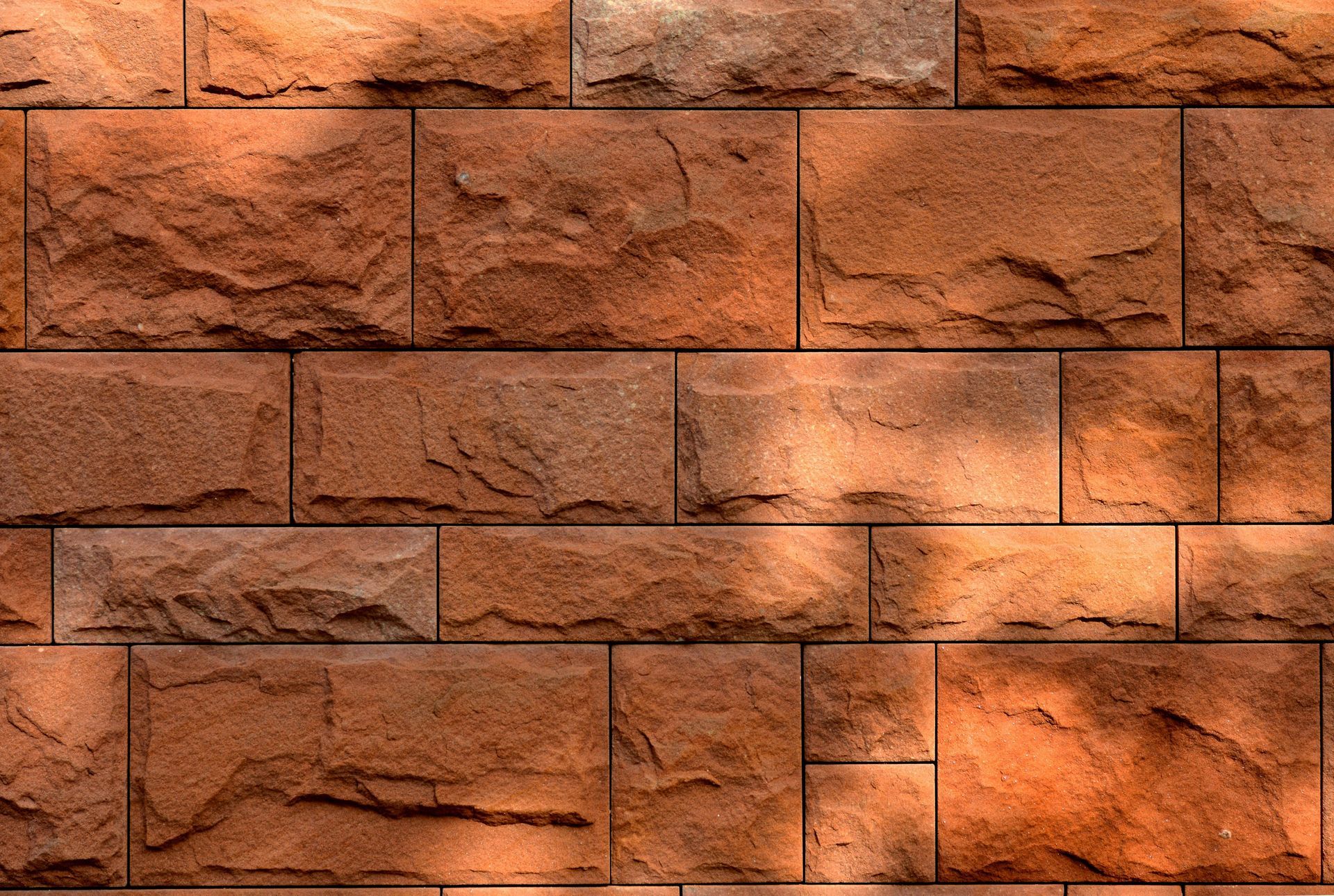 Brick wall, reddish-brown color, textured surface, with sunlight and shadows.