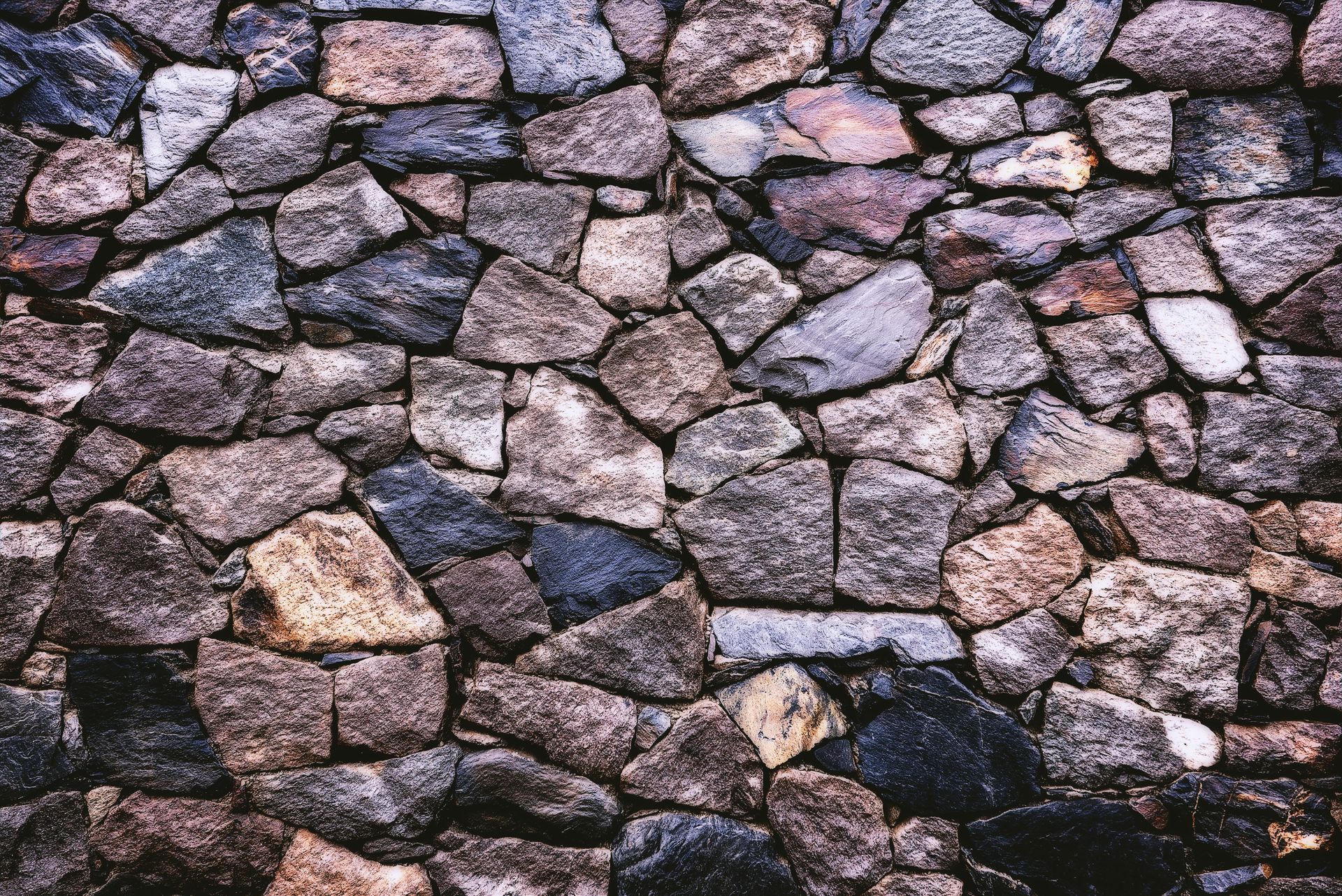 Stone wall made of various sized and colored rocks.
