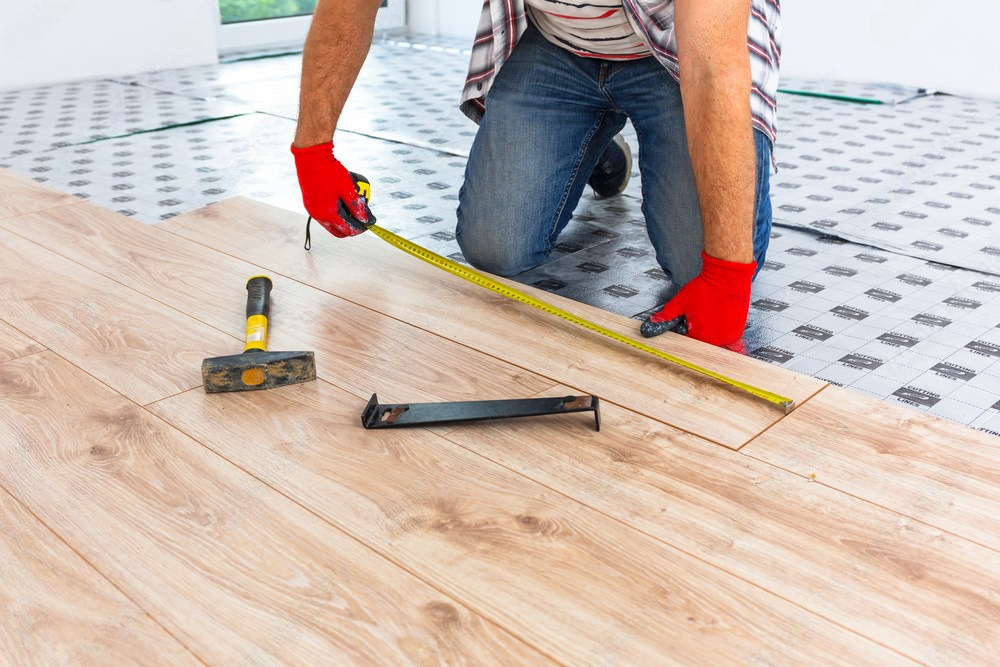 a man is measuring a wooden floor with a tape measure .