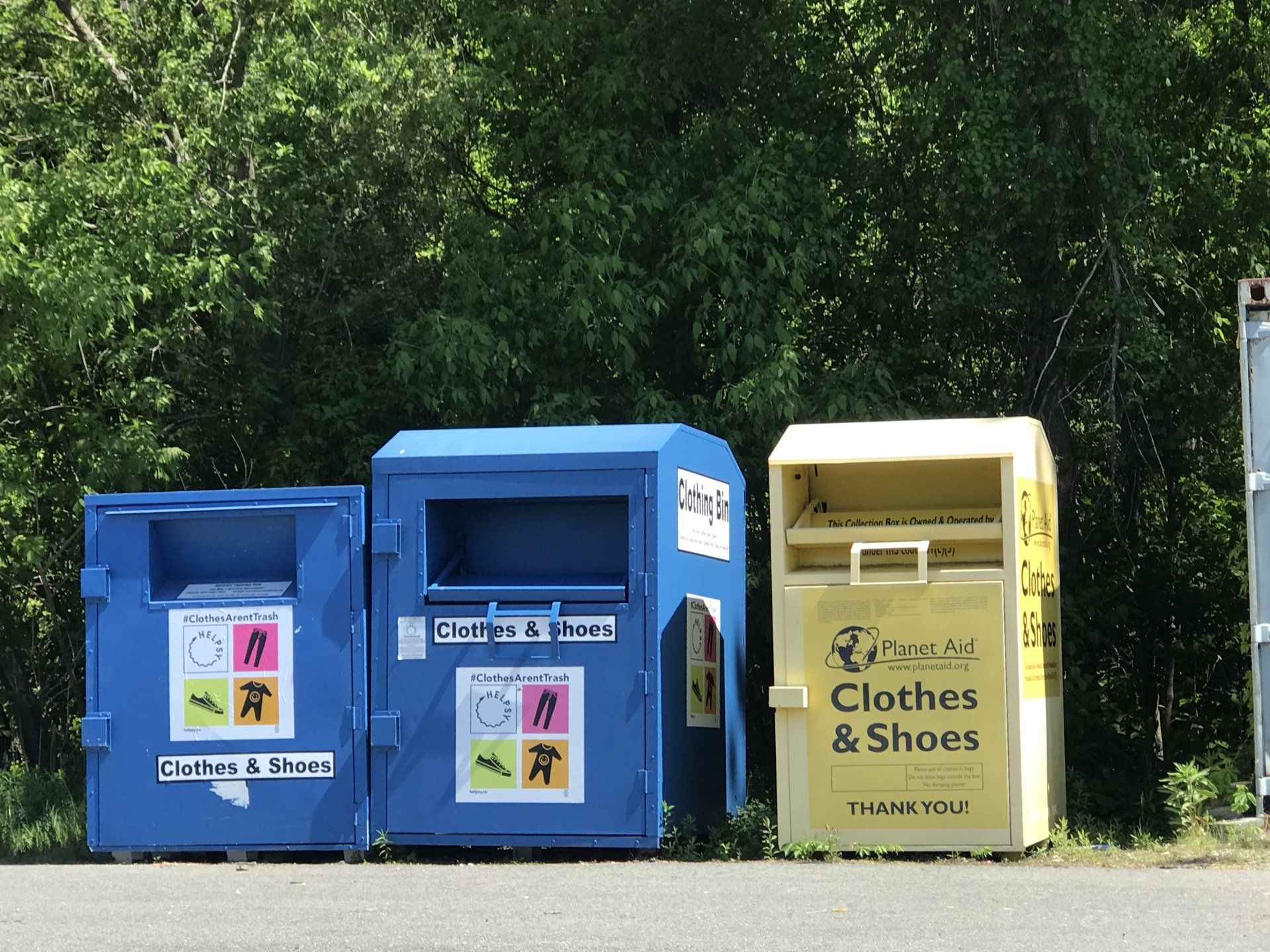 Two large blue donation bins and a large yellow donation bin from Planet Aid