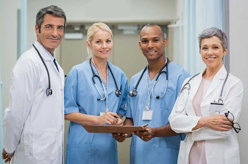 A group of doctors and nurses are standing next to each other in a hospital hallway.