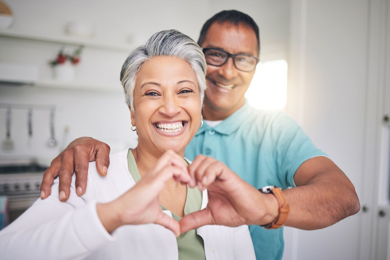 A man and a woman are making a heart shape with their hands.