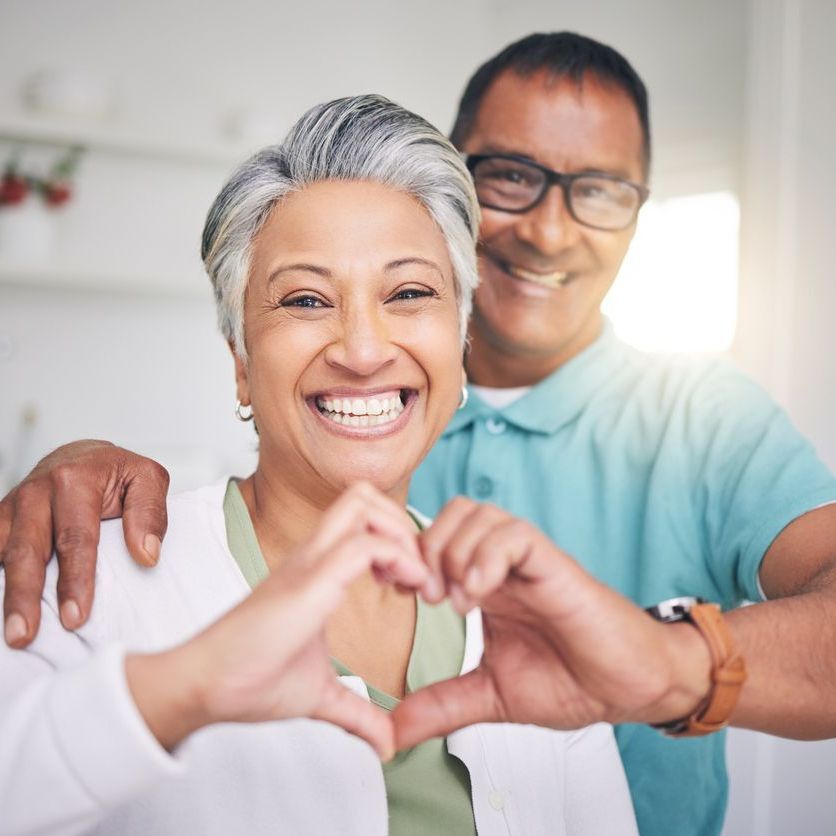 Patient making a heart with her hands with a doctor behind her