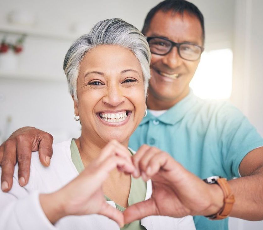 A man and a woman are making a heart shape with their hands.