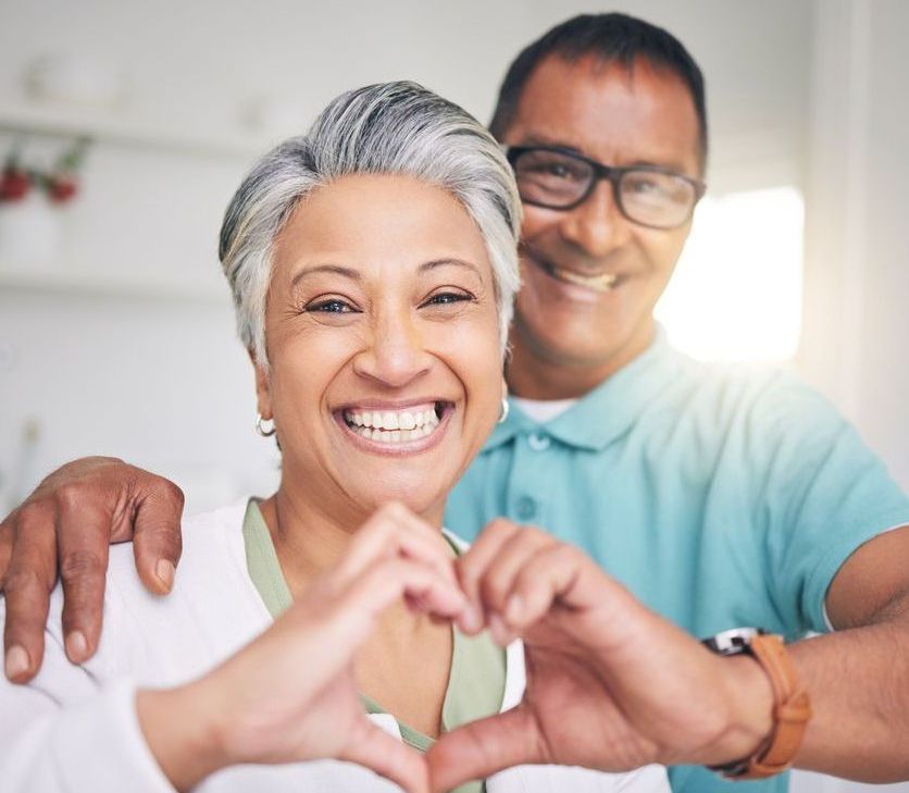 A man and a woman are making a heart shape with their hands.