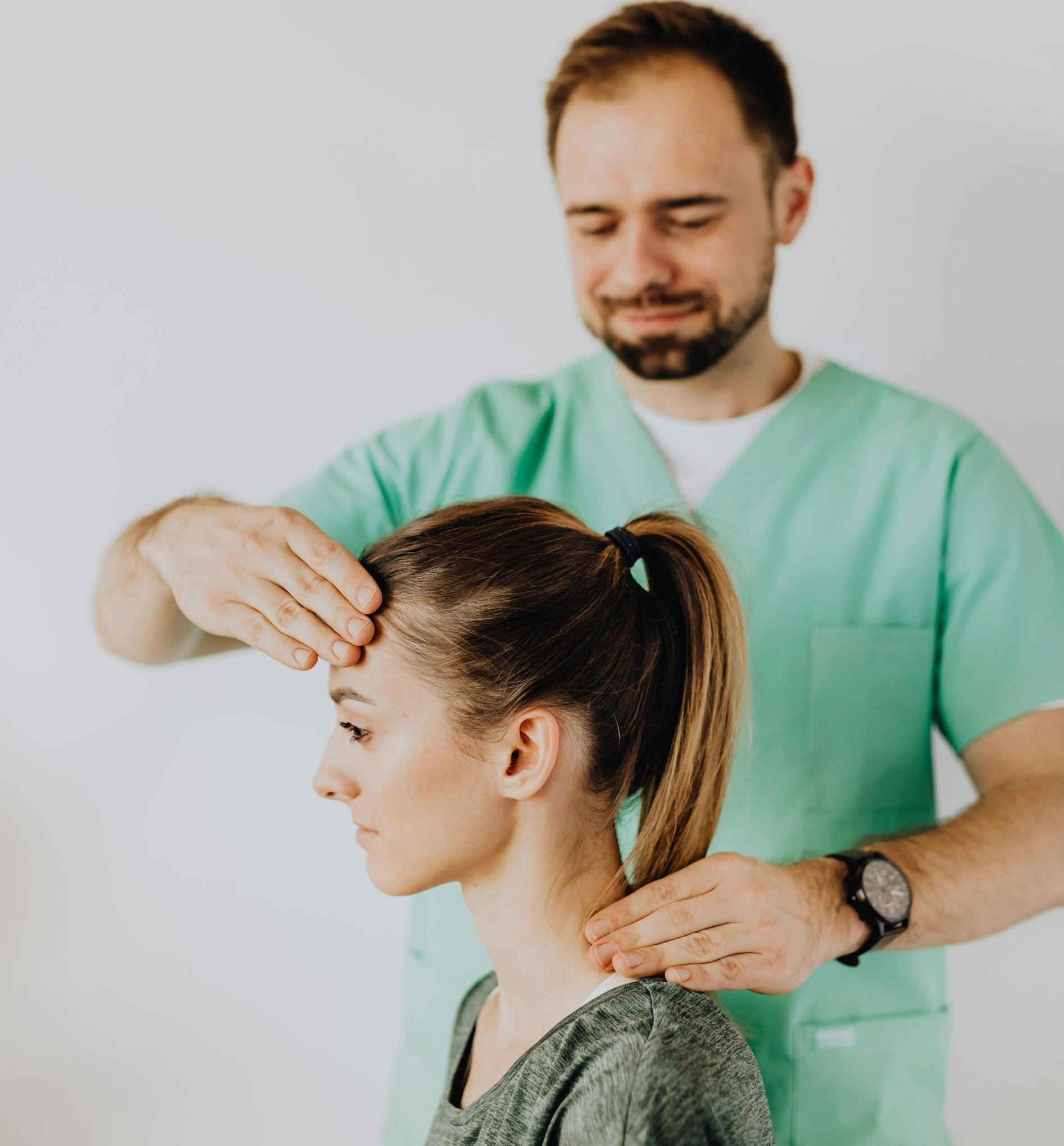 A man in a green scrubs is giving a woman a head massage.