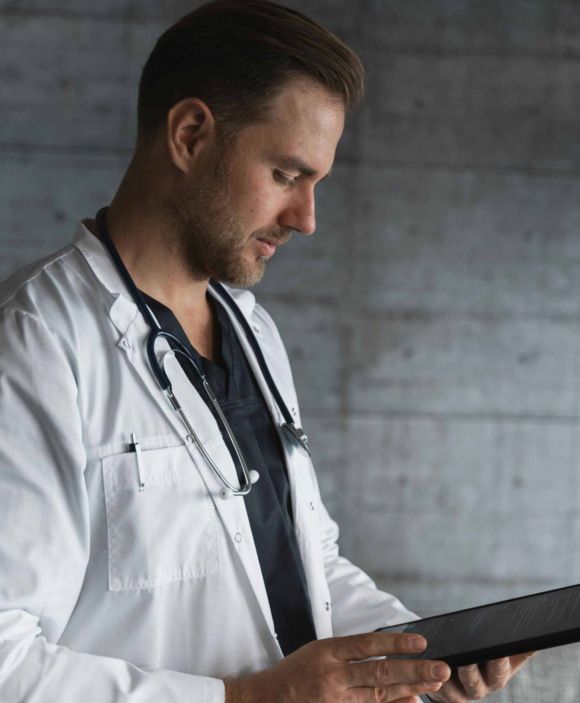 A doctor in a lab coat is using a tablet computer.