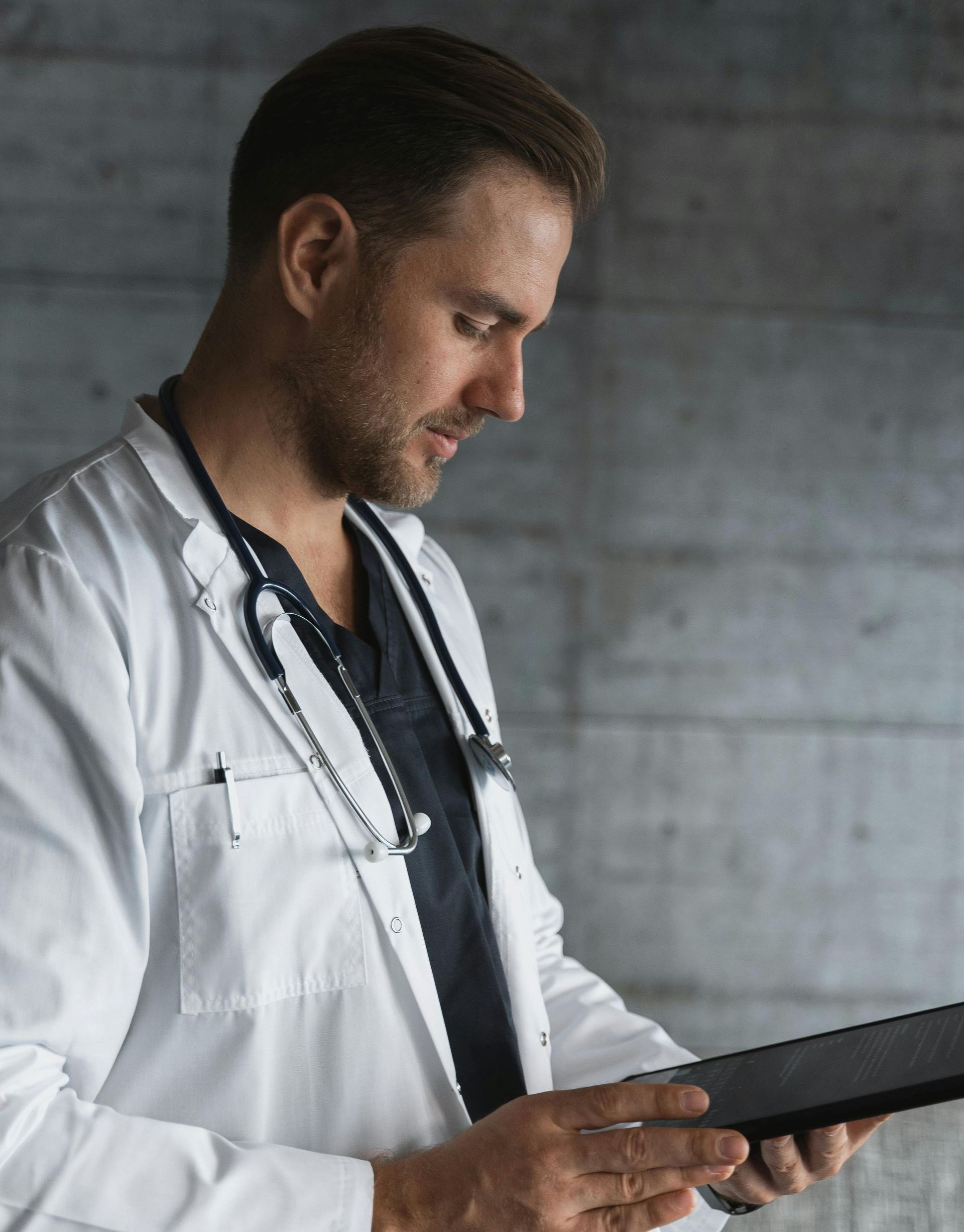 A doctor in a lab coat is using a tablet computer.