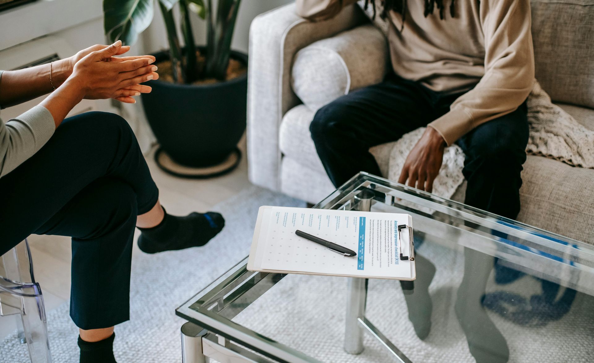 A man and a woman are sitting on a couch talking to each other.