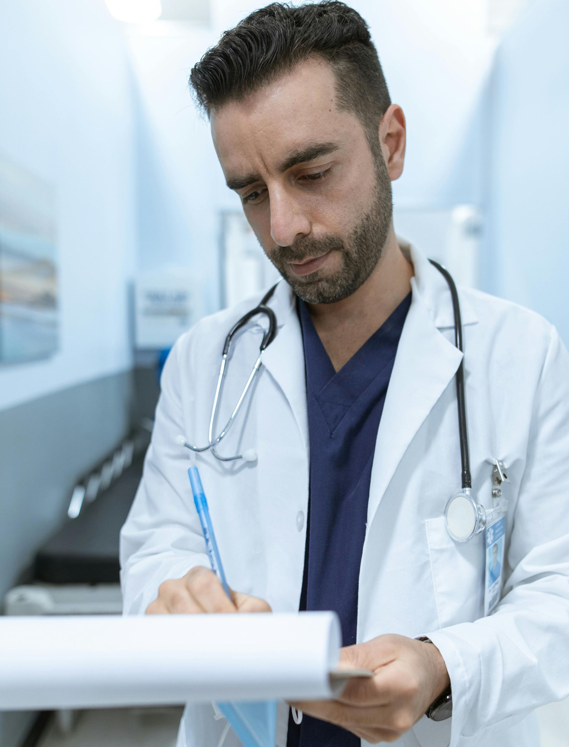A doctor with a stethoscope around his neck is writing on a piece of paper.