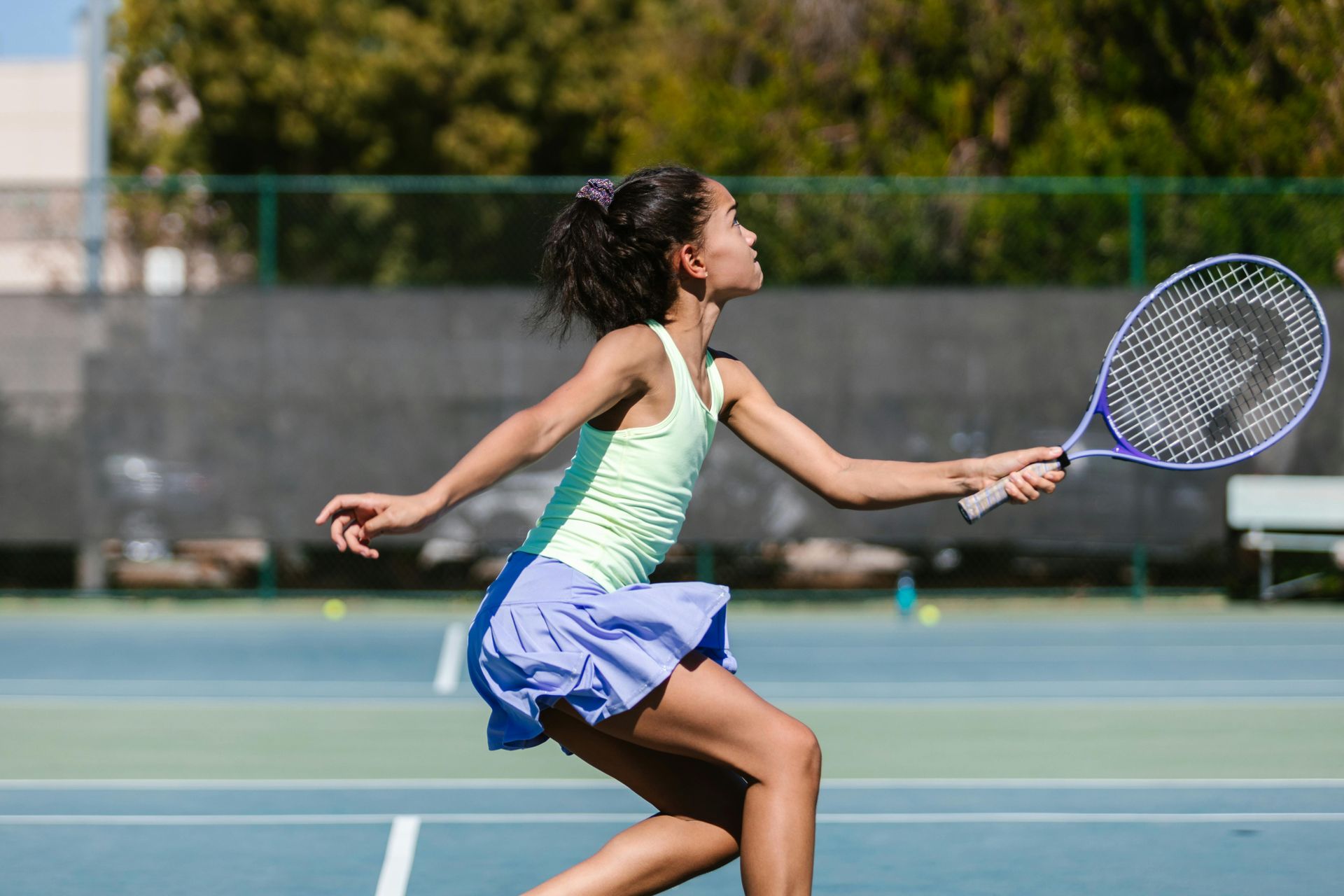 A young girl is playing tennis on a tennis court.