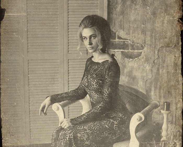 a black and white photo of a woman in a lace dress sitting in a chair .