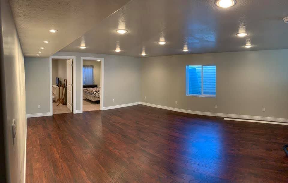 A large empty room with hardwood floors and a window.