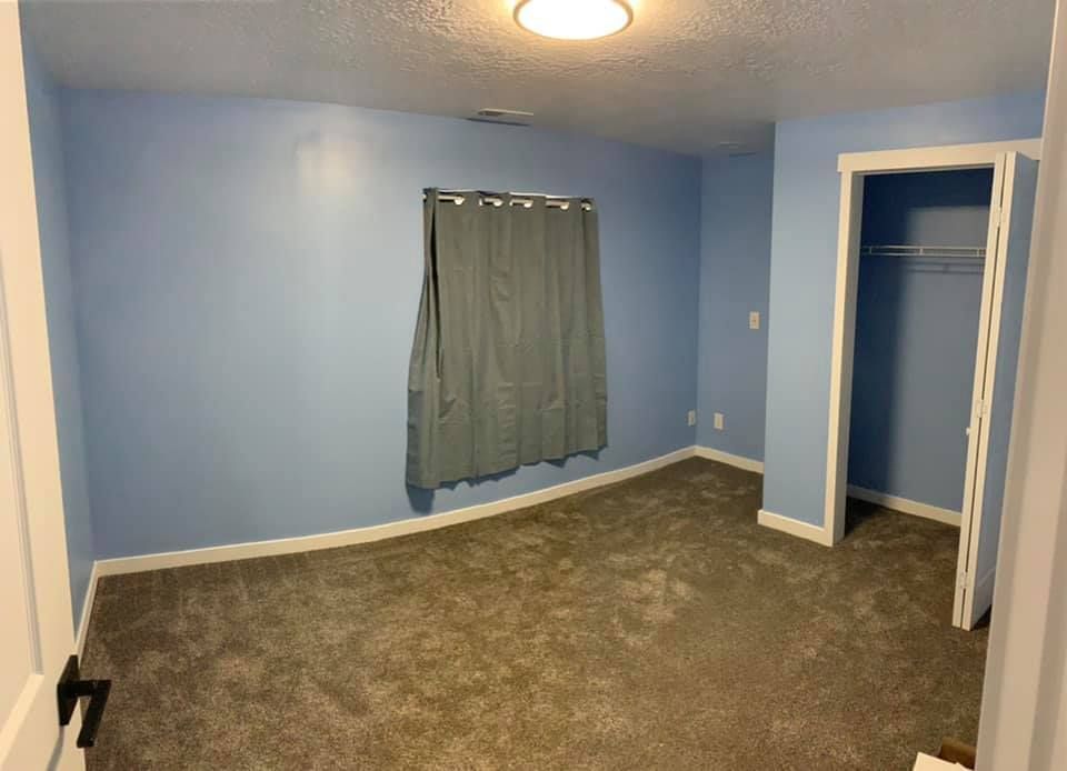 An empty bedroom with blue walls and a closet