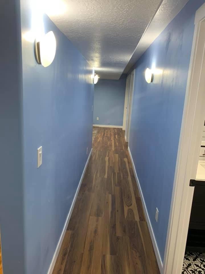 A long hallway with blue walls and wooden floors.