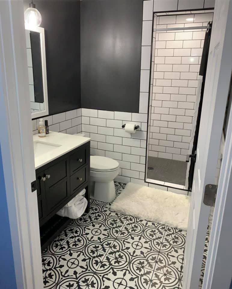 A bathroom with a toilet , sink , mirror and shower.