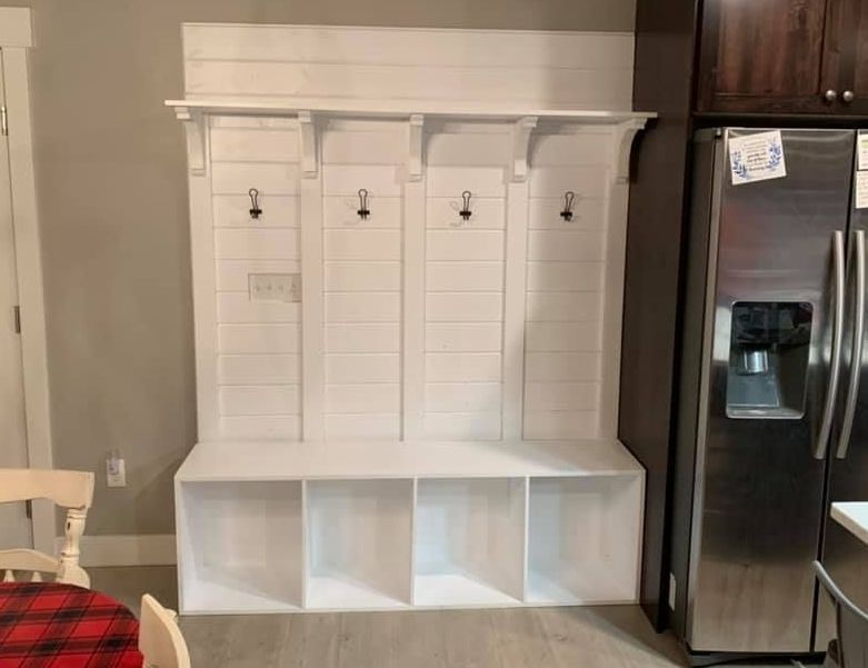 A kitchen with a stainless steel refrigerator and a white bench with hooks.