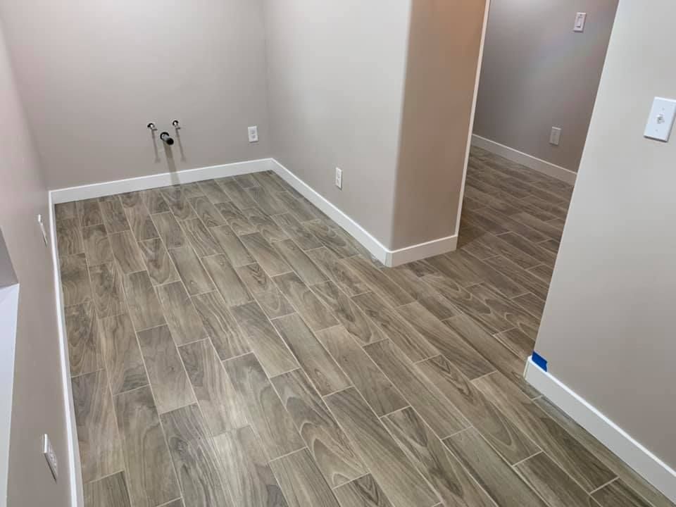 A laundry room with a wooden floor and white trim.
