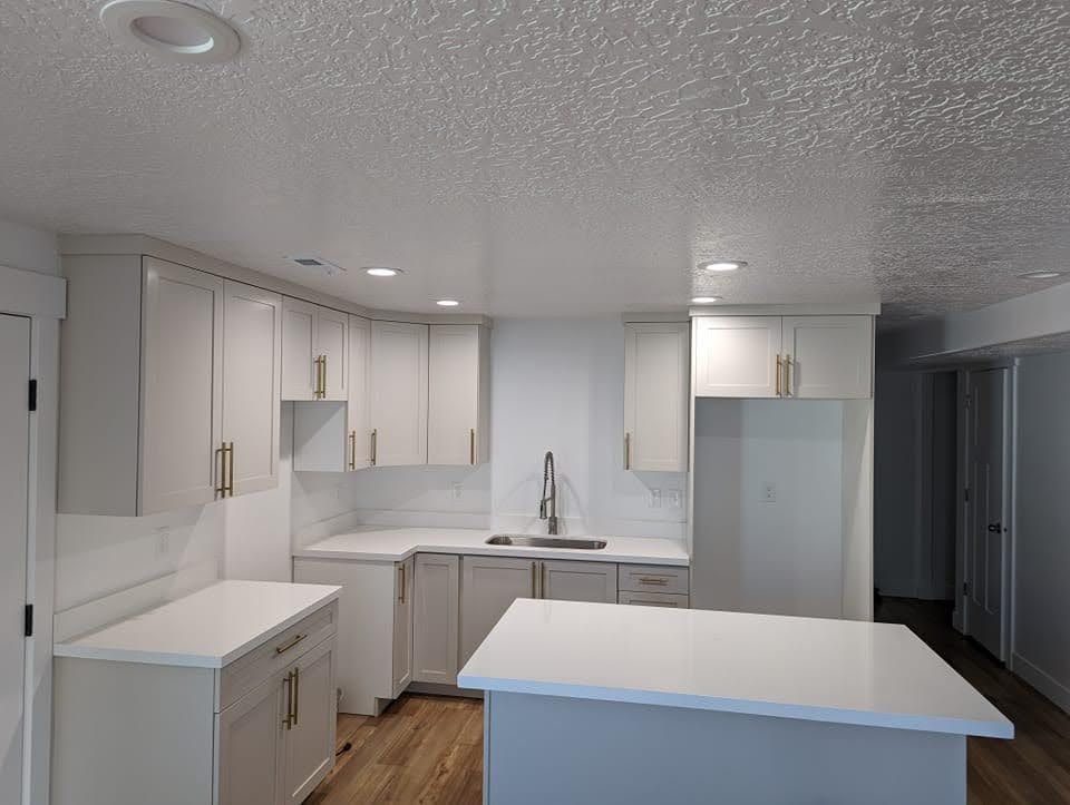 A kitchen with white cabinets and a large island in the middle.
