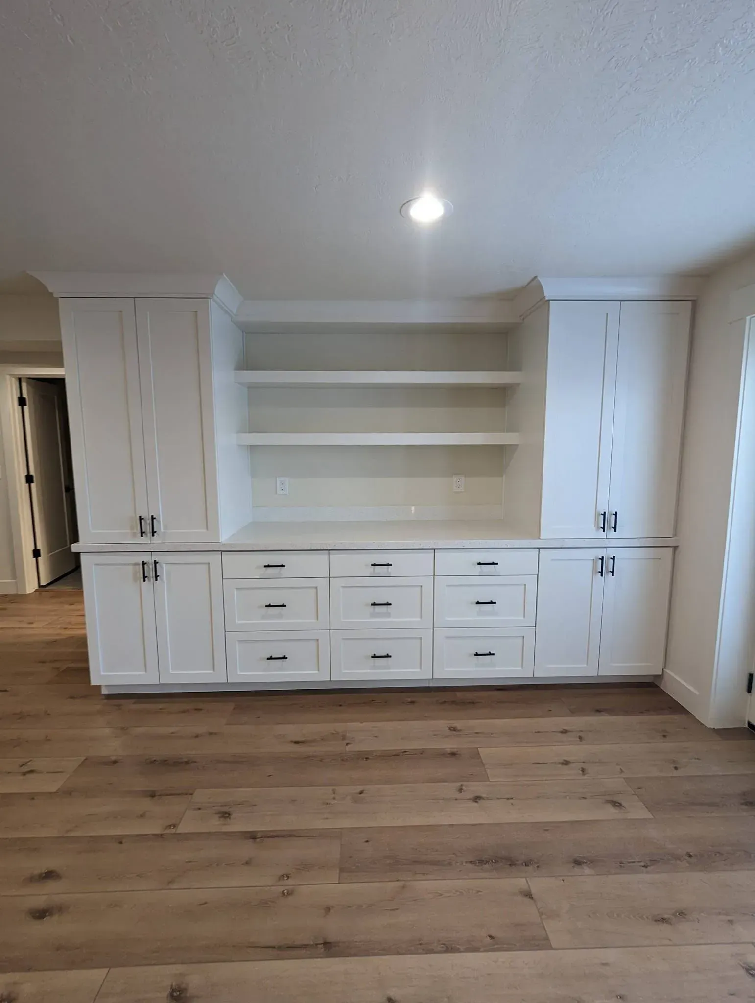 A living room with hardwood floors and white cabinets.