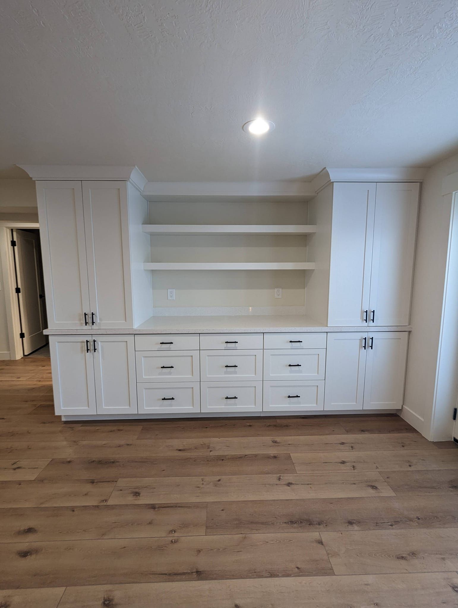 A living room with hardwood floors and white cabinets.