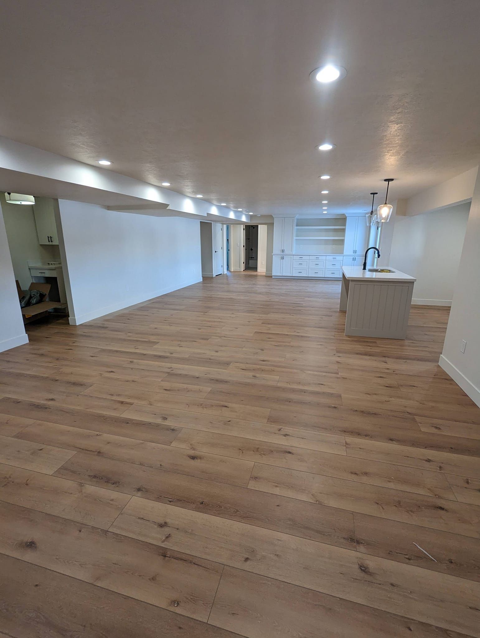 A large empty room with hardwood floors and white walls.