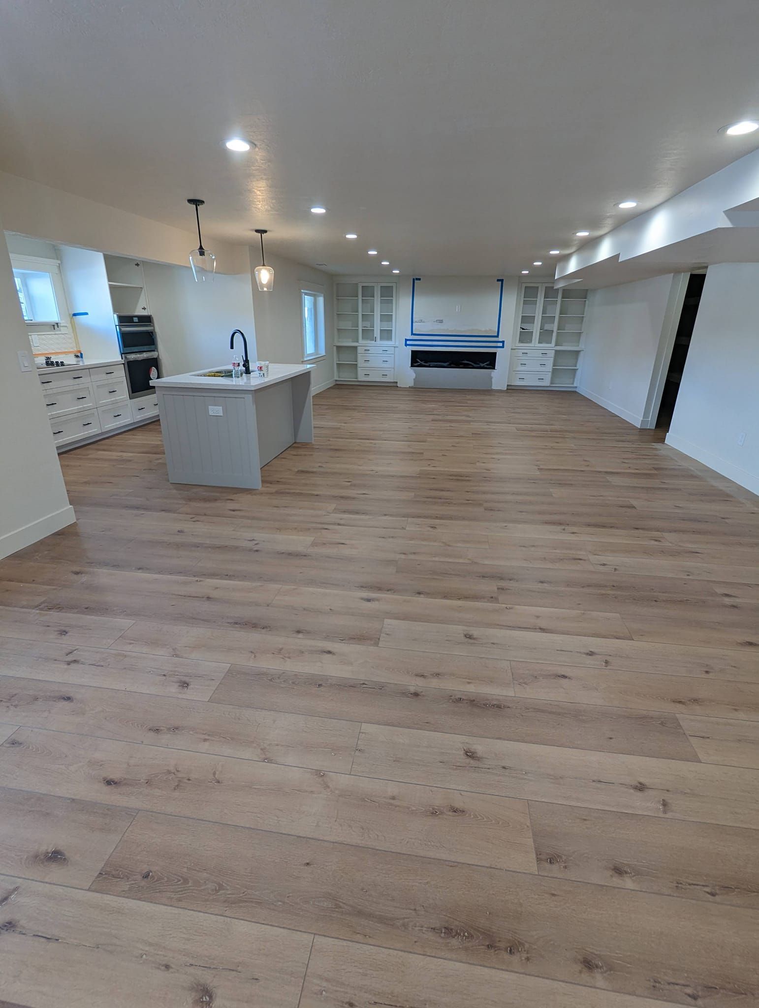 A large empty room with hardwood floors and a kitchen.