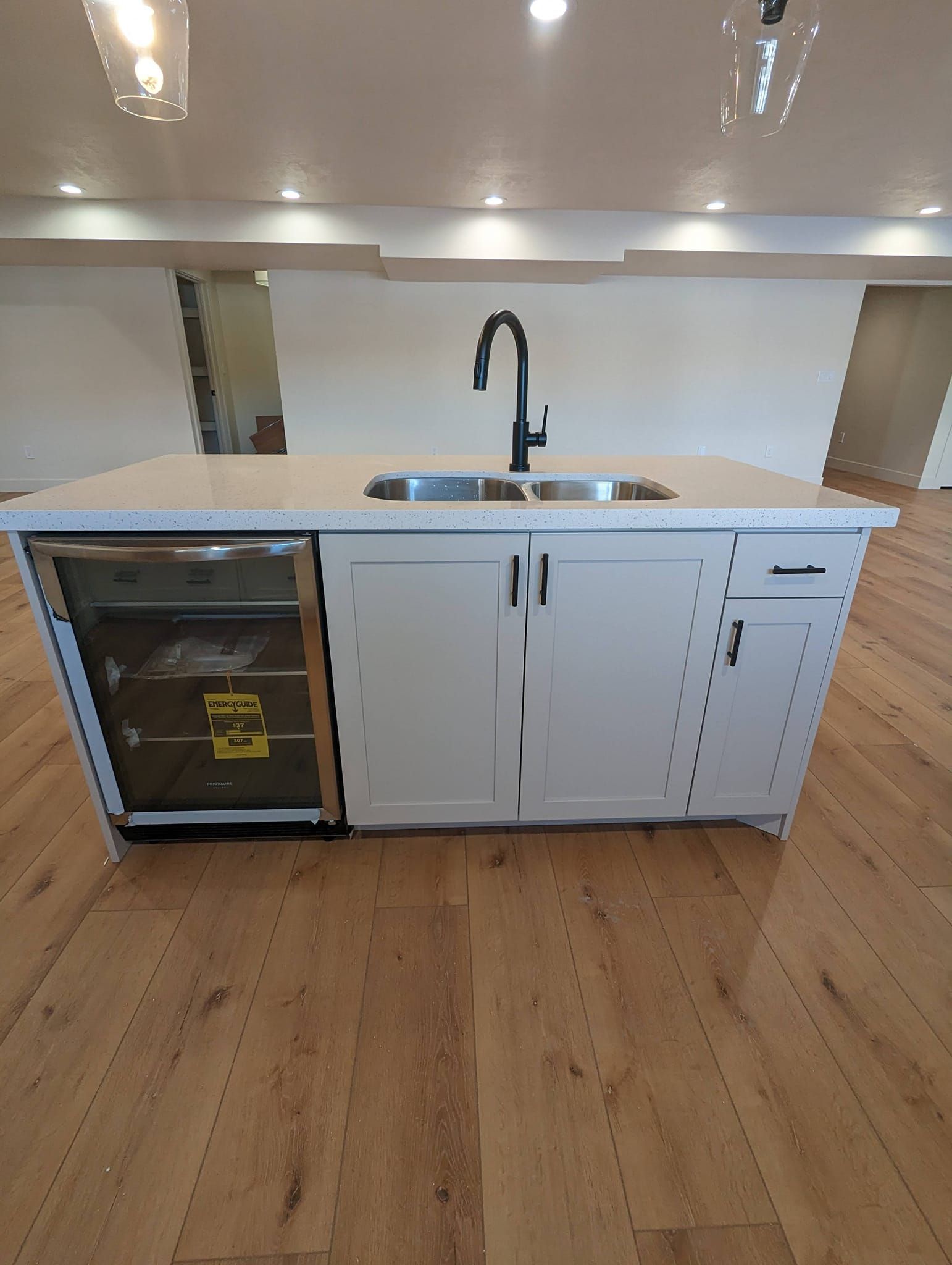 A kitchen island with a sink and a refrigerator underneath it.