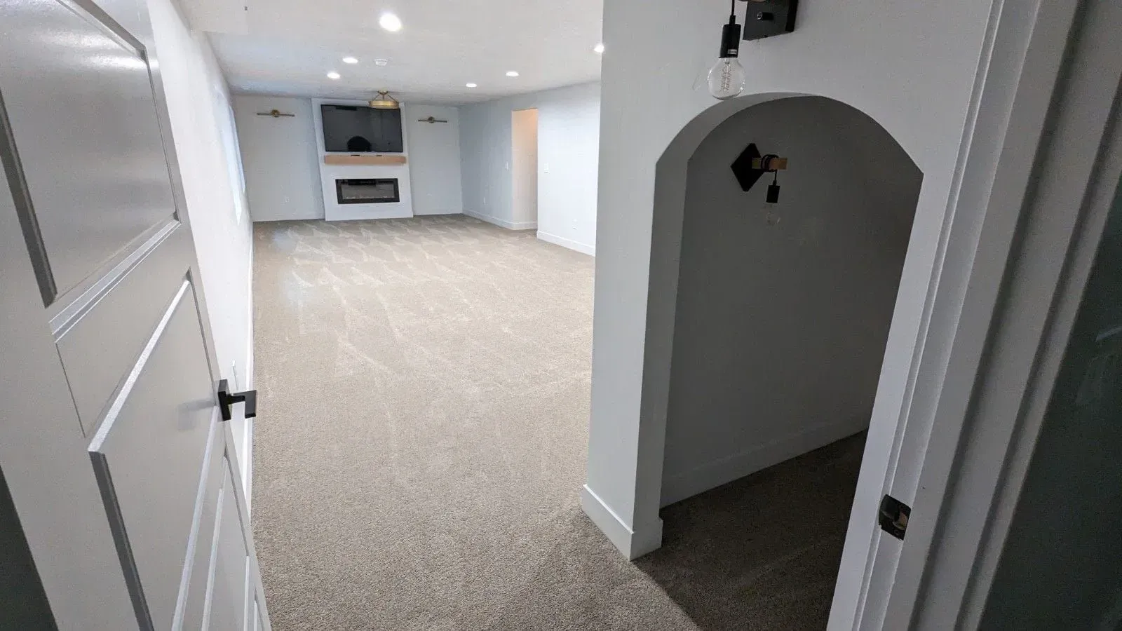 An empty basement with carpeted floors and a fireplace.