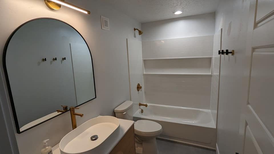 A bathroom with a sink , toilet , tub and mirror.