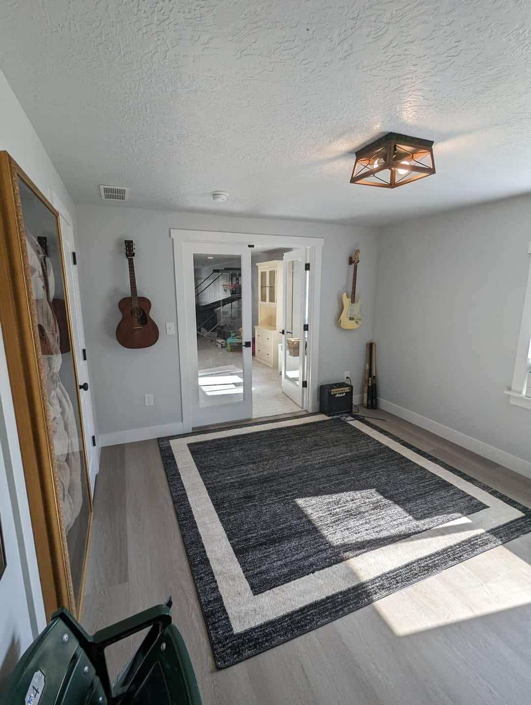 A living room with a rug and guitars on the wall.