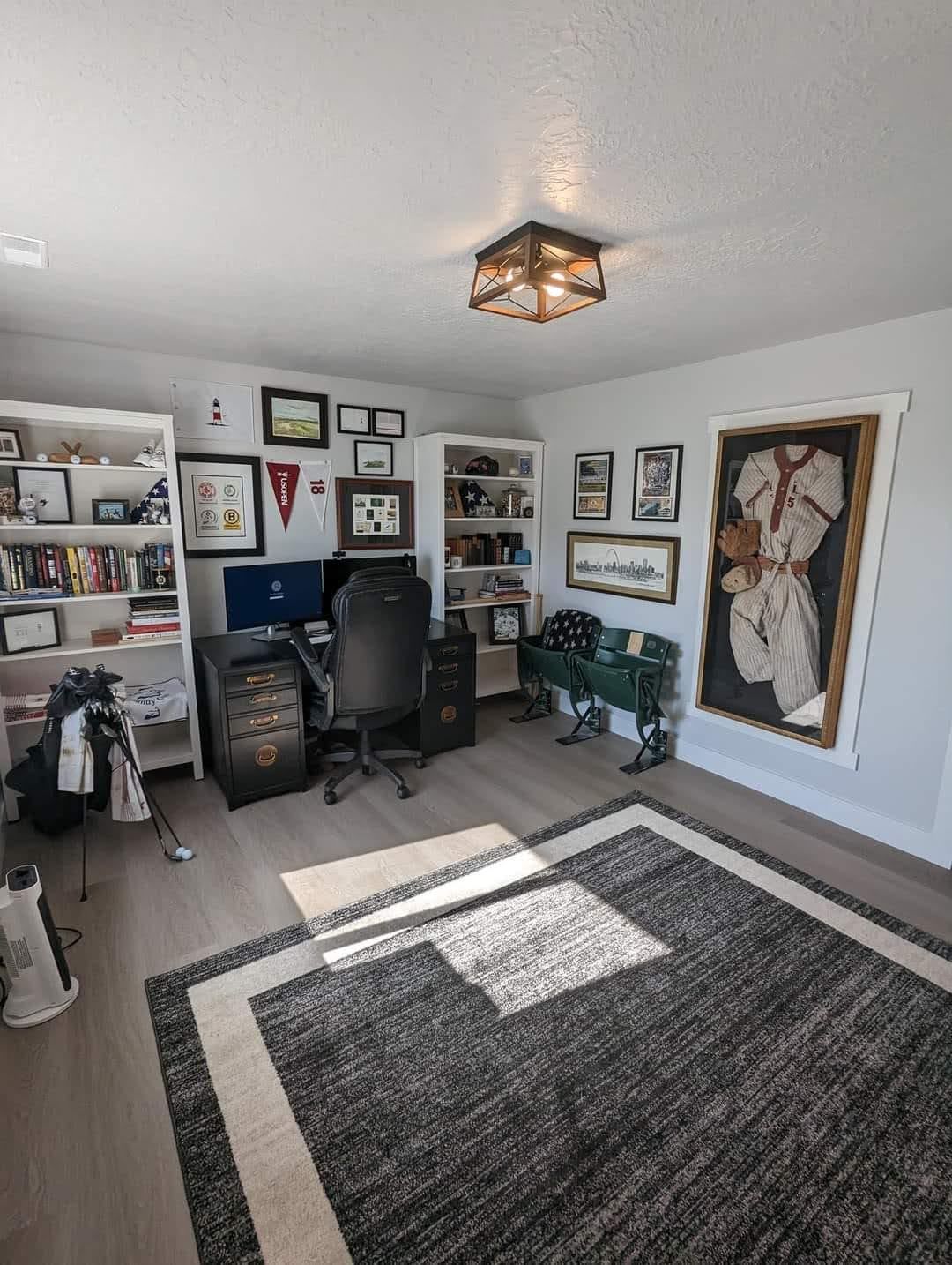 A room with a desk , chair , and a rug.