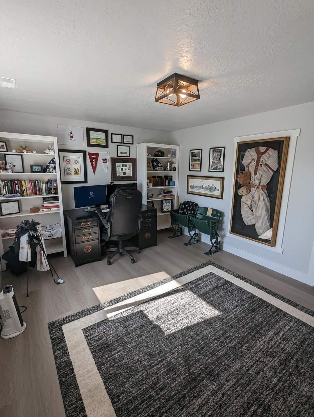 A room with a rug , a desk , a chair and a computer.