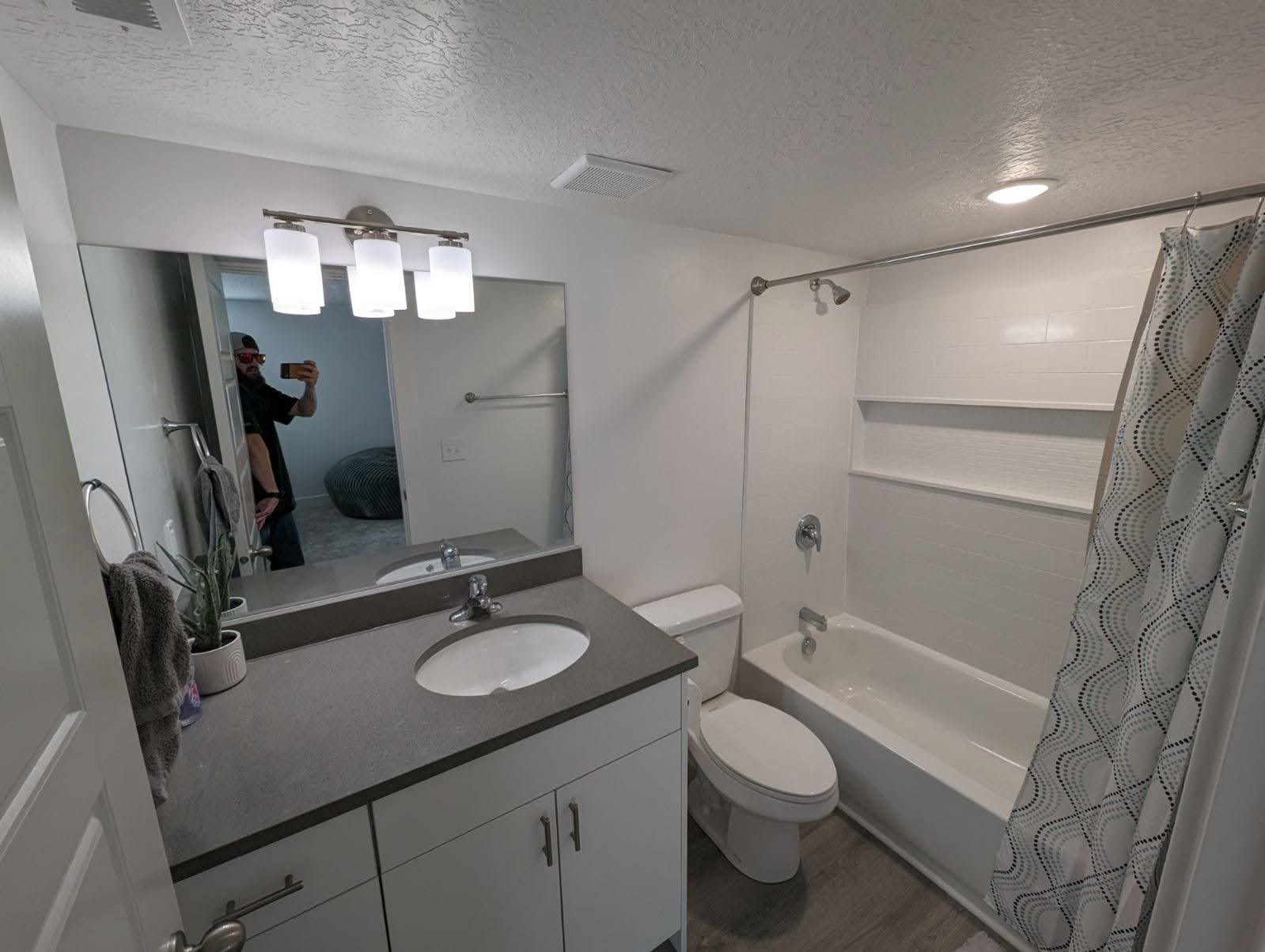 A bathroom with a toilet , sink , tub and mirror