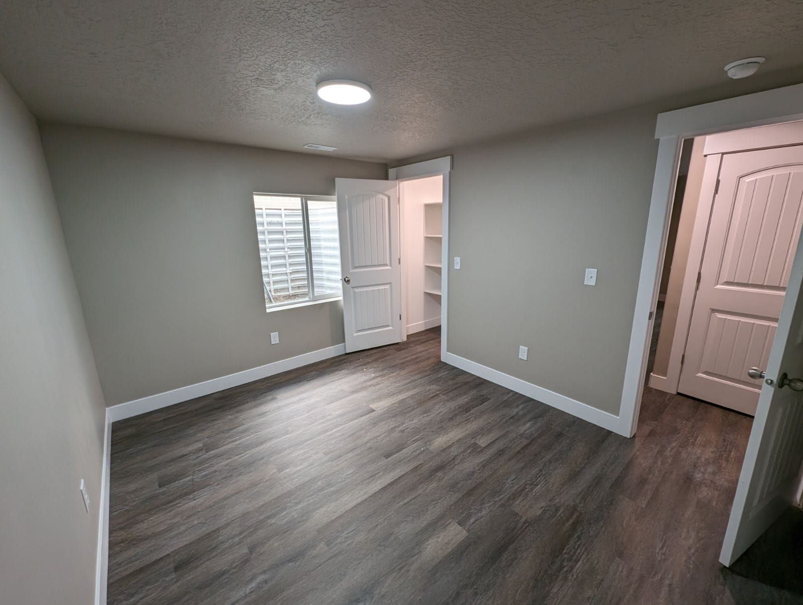 An empty room with hardwood floors and a window.