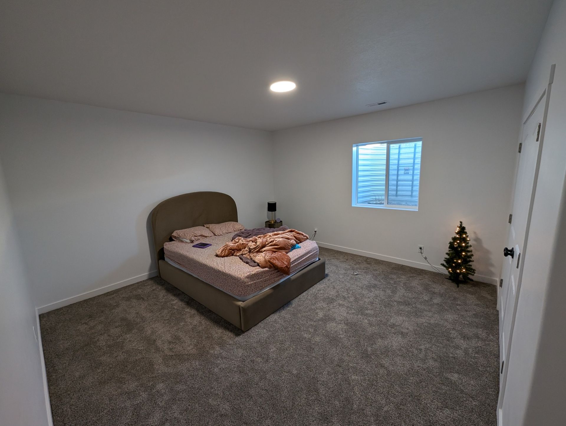 A bedroom with a bed and a christmas tree in it.