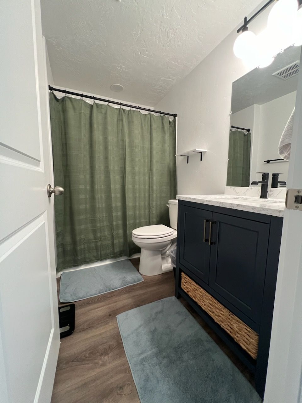 A bathroom with a toilet , sink , mirror and shower curtain.