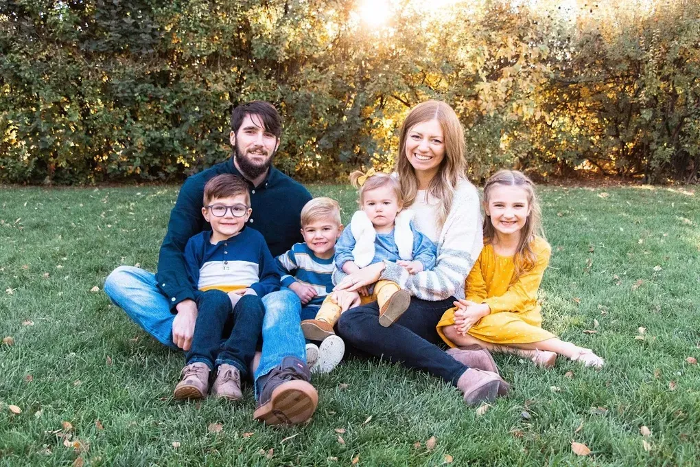 A family is sitting on the grass posing for a picture.