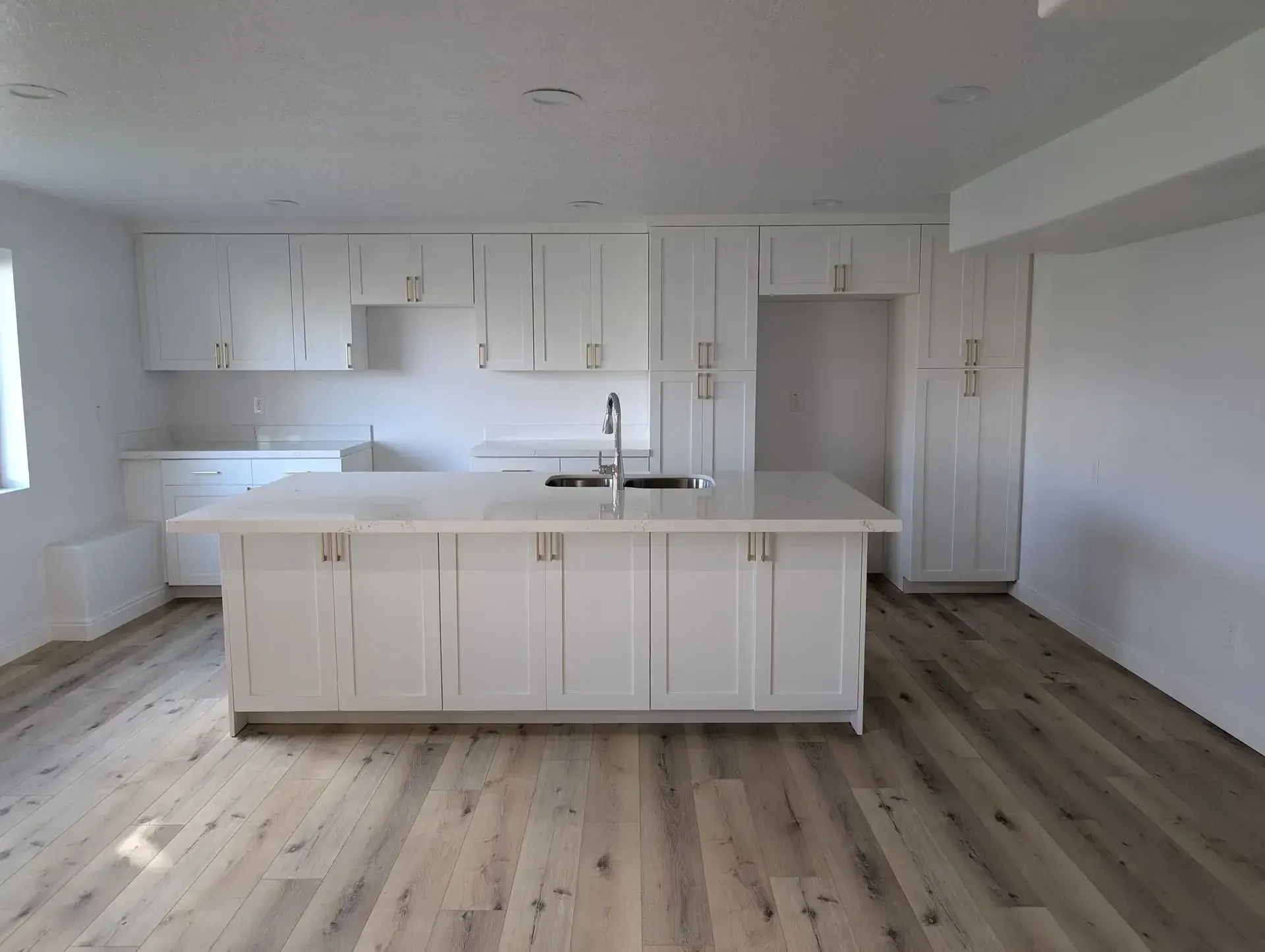 An empty kitchen with white cabinets and a large island