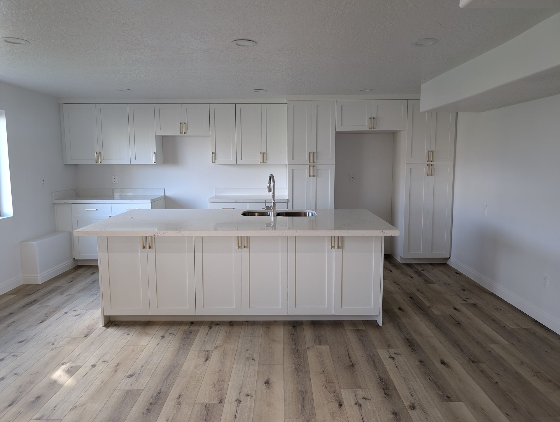 An empty kitchen with white cabinets and a large island