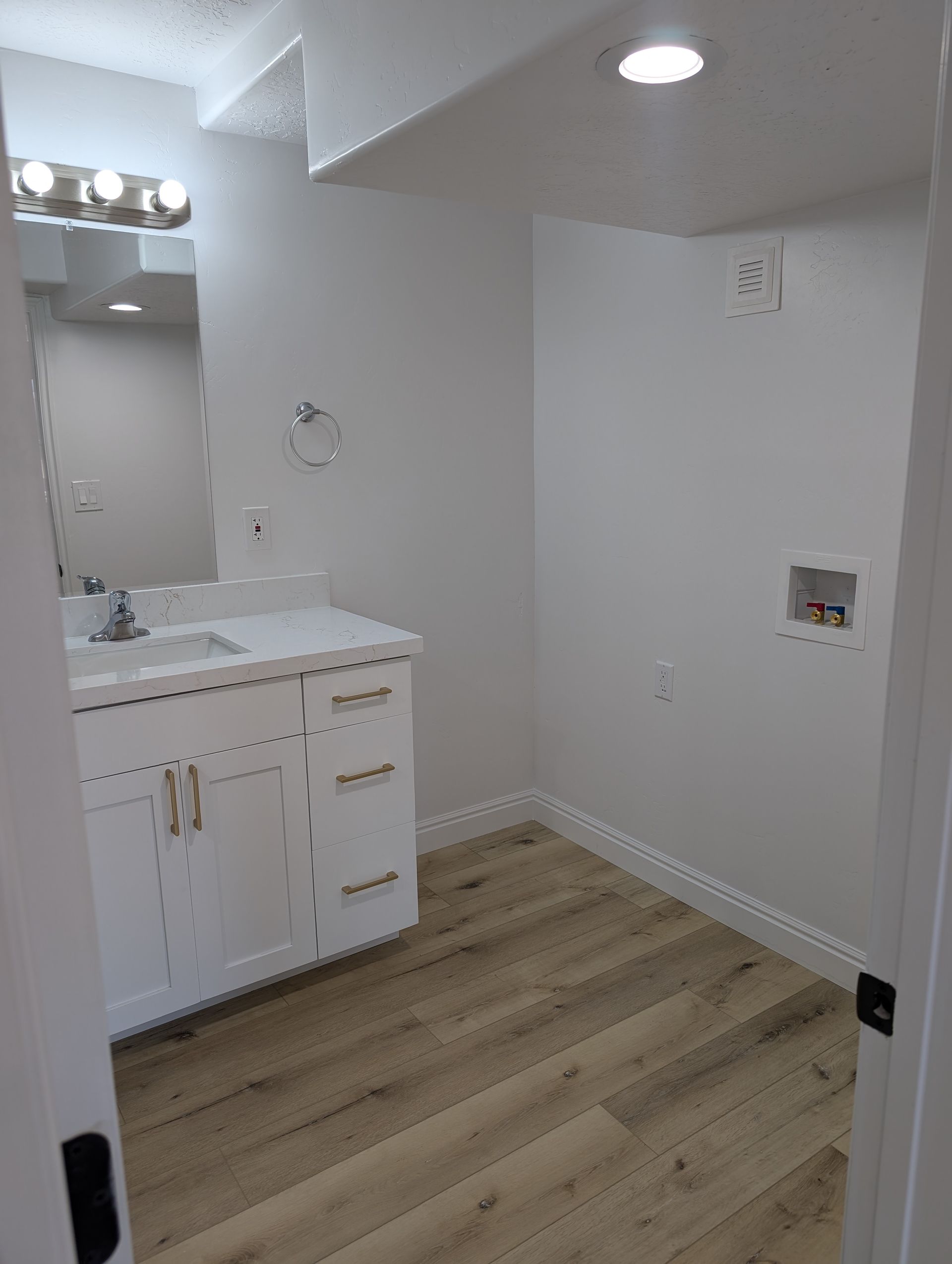 A bathroom with a sink , mirror , and hardwood floor.